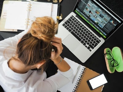 A woman holding her head is desperate because she can't find her lost phone in Belgium using her computer and her old iPhone.